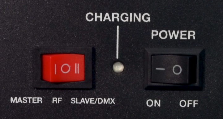 A black device control panel showing a red three-position mode switch on the left labeled MASTER, RF, and SLAVE/DMX(selected); a central LED indicator labeled CHARGING; and a black POWER switch on the right labeled ON and OFF.